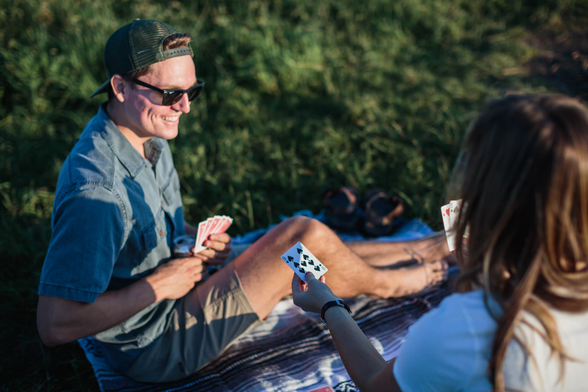 guy in sunglasses playing cards on grassy mountain, Nashville engagement, couples mountain, mountain engagement, couples camping, dog photography, Knoxville, couples hiking, camping with dog, North Carolina hiking, summer engagement photos, Tennessee Photography, Tennessee Photographer, Tennessee Photos, Tennessee Engagement Photography, Tennessee Engagement Photos, Tennessee Engagement Photographer, Tennessee Portrait Photographer, Nashville Engagement Photographer, Nashville Engagement Photos, Knoxville Engagement, Nashville Lifestyle Photographer, Nashville Lifestyle Photography, Nashville Lifestyle Photos, Creative Portraits